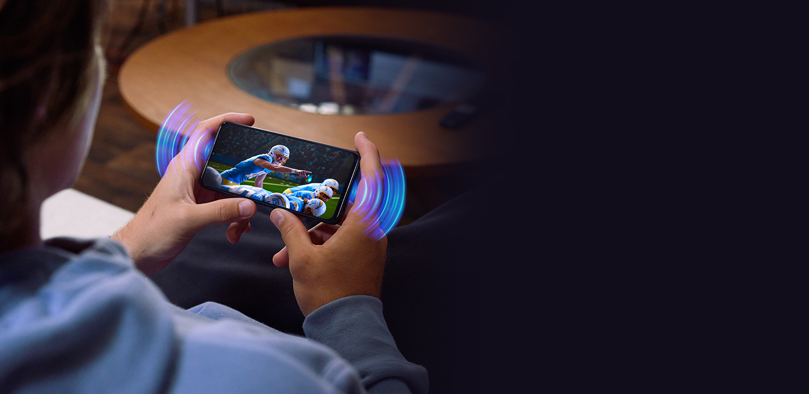 hands holding a phone watching football